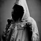 Vygenerováno pomocí umělé inteligence Craiyon-v2 dotazem: Old black and white photo of Hastur, king in yellow, demonic hooded figure covered in tattered clothing. Černobílá fotografie podivné zahalené postavy v potrhaných šatech bez viditelného obličeje.